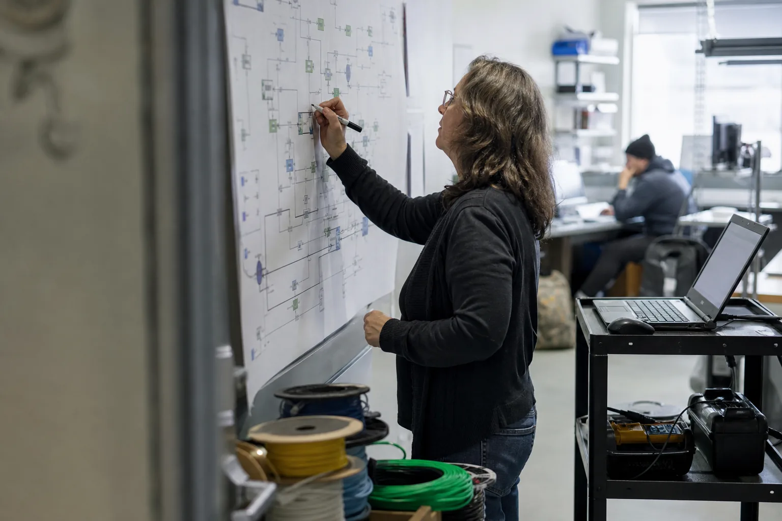 A county IT engineer reviewing a cloud network diagram printed on large paper taped to the wall