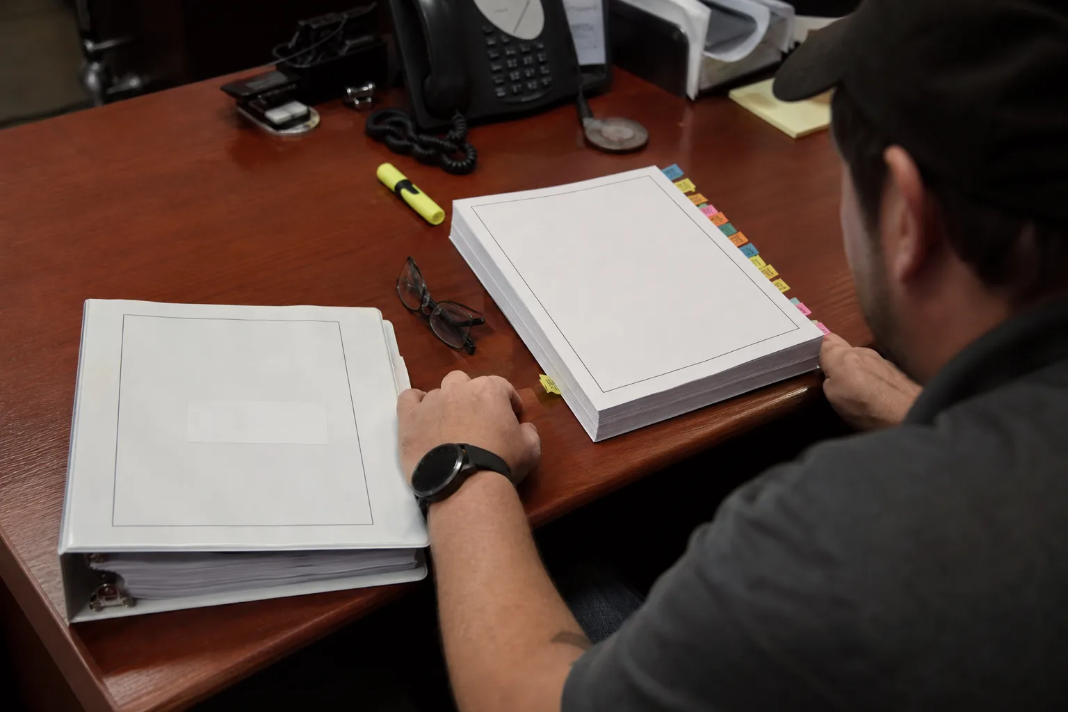 Two printed versions of a security policy side by side on a desk with tabs marking changed sections