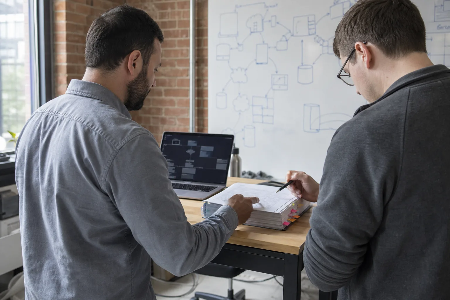 Engineers at a gov-tech software company reviewing a printed agency security questionnaire together at a standing desk