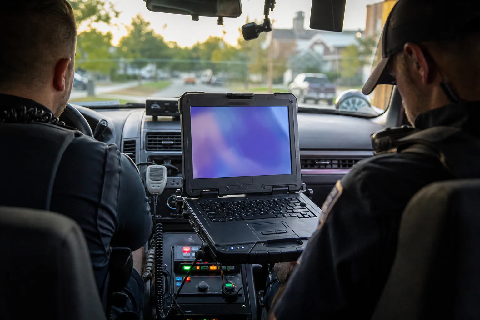 A mobile data terminal mounted between the seats of a patrol car showing a dispatch application